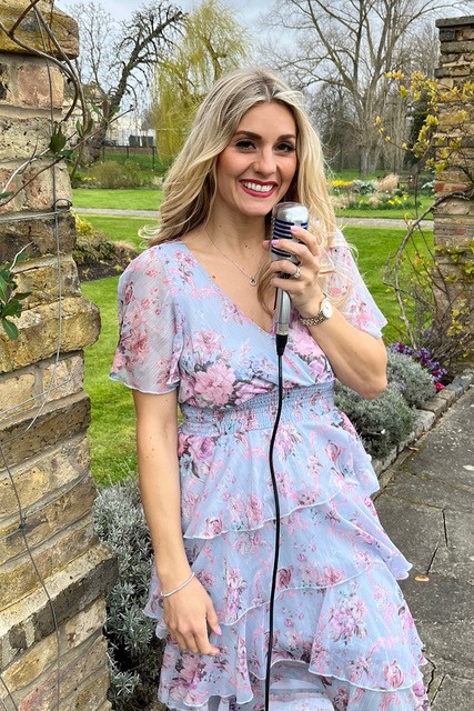 Lady singing into 50s style microphone in bluish flowery dress