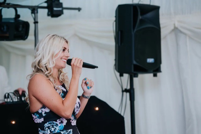 Woman singing in front of PA system
